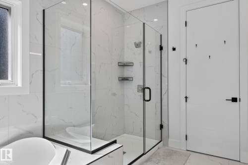 Glass-enclosed shower with matte black framing, featuring a rainfall showerhead and integrated shelving - 16304 19 Avenue Sw, Edmonton, AB 