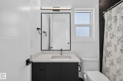 Contemporary bathroom featuring a modern vanity with a rectangular sink, a framed mirror, and a window with white trim - 16304 19 Avenue Sw, Edmonton, AB 