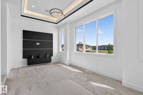 Bright interior space featuring a recessed ceiling with accent lighting and a modern chandelier - 16304 19 Avenue Sw, Edmonton, AB 