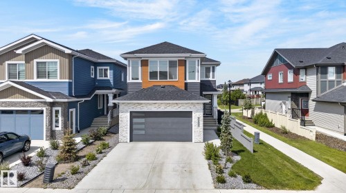 Modern two-story residence featuring a dark gray garage door with horizontal frosted glass inserts, a light-colored brick facade, and dark gray siding - 16304 19 Avenue Sw, Edmonton, AB 