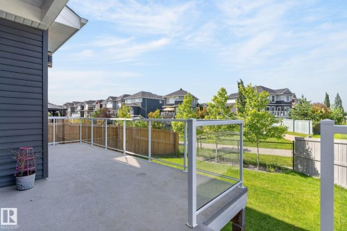 Spacious exterior deck with glass panel railing and composite decking, offering an open-air extension of the home - 16304 19 Avenue Sw, Edmonton, AB 
