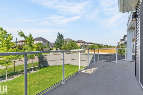 Concrete patio featuring glass panel railings with metal posts, exterior wall siding, and an attached outdoor light fixture - 16304 19 Avenue Sw, Edmonton, AB 