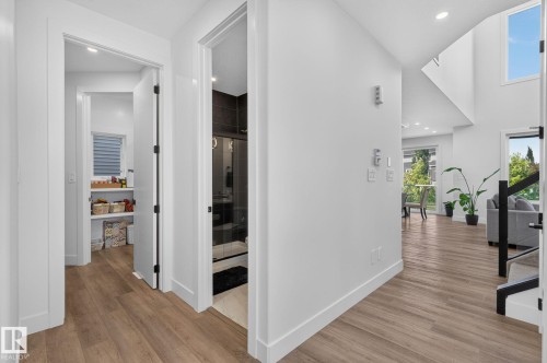 Hallway featuring wood-finish flooring, white walls, and recessed lighting - 16304 19 Avenue Sw, Edmonton, AB 