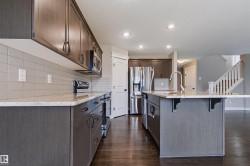 Kitchen featuring wood-finish flooring, recessed lighting, stone countertops, and stainless steel appliances - 