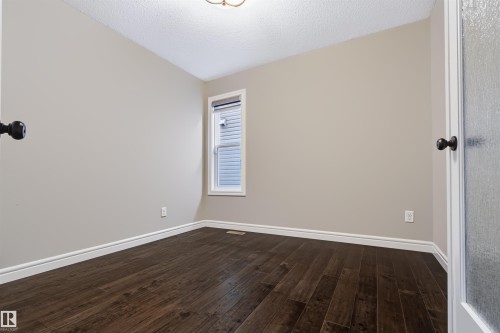Wood-finish flooring, neutral wall paint, white trim, and a window with blinds - 1420 158 Street Sw, Edmonton, AB 
