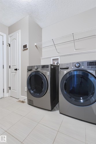 Laundry area featuring light-toned tile flooring, light gray walls, and white wire shelving - 1420 158 Street Sw, Edmonton, AB 