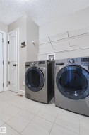 Laundry area featuring light-toned tile flooring, light gray walls, and white wire shelving - 