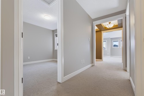 Neutral wall color, light carpeting, white trim, recessed tray ceiling, and a flush mount light fixture - 1420 158 Street Sw, Edmonton, AB 