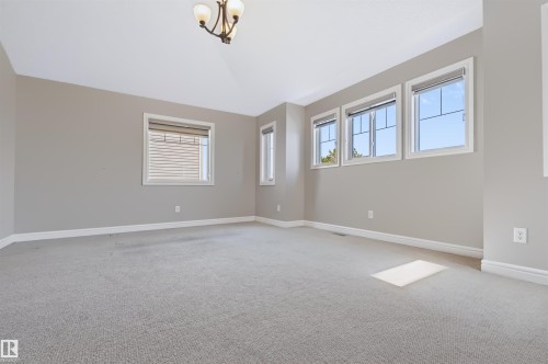 Neutral wall tones, multiple windows with white trim, vaulted ceiling, and recessed lighting fixture - 1420 158 Street Sw, Edmonton, AB 