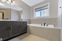Built-in soaker tub with dark bronze fixtures, tile surround, and an integrated window - 
