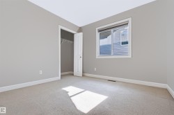 Neutral tone carpeted flooring, light grey painted walls, white trim, and a built-in closet with wire shelving - 