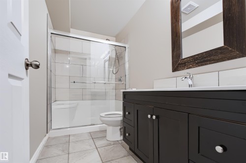 Bathroom featuring a dark wood finish vanity with integrated sink, chrome faucet, and white subway tile backsplash - 1420 158 Street Sw, Edmonton, AB 