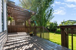Spacious wood deck with a built-in pergola, privacy lattice, and wood railings overlooking a large grassy yard - 