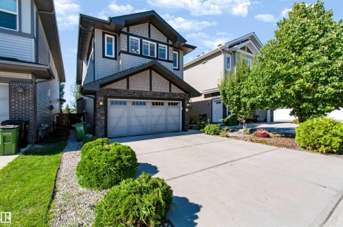 Contemporary exterior featuring mixed siding, stone accents, multiple windows, and an integrated two-car garage - 1420 158 Street Sw, Edmonton, AB 