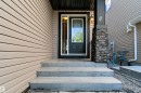 Front entry with concrete steps, a dark-paneled door, and a decorative stone-clad column - 1420 158 Street Sw, Edmonton, AB 