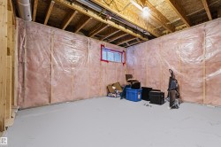 Unfinished basement featuring exposed wood framing, ceiling joists, and insulation - 