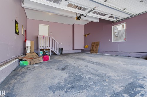 Roll-up garage door with automatic opener, concrete flooring, window for natural light, and interior access door - 1420 158 Street Sw, Edmonton, AB 