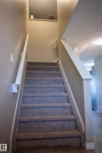 Carpeted staircase with white handrails and neutral wall finishes - 9014 Cooper Link Link Sw, Edmonton, AB 