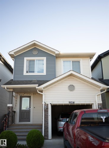 Two-story exterior with multi-toned siding, attached single-car garage, covered entry, and front porch with steps - 9014 Cooper Link Link Sw, Edmonton, AB 