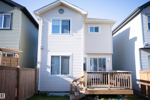 Two-story exterior with light-colored siding, multiple windows, and a wooden deck with railings - 9014 Cooper Link Link Sw, Edmonton, AB 