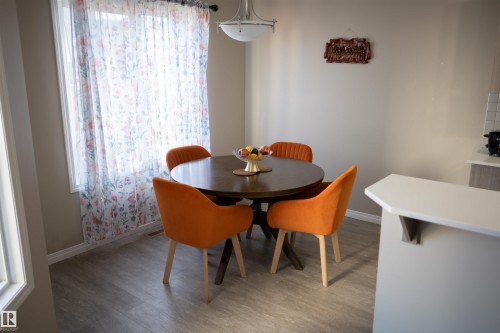 Wood-finish flooring, ample natural light from a large window, neutral wall paint, and a built-in kitchen counter with a light-colored surface - 9014 Cooper Link Link Sw, Edmonton, AB 