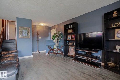 Wood-finish flooring, staircase with dark treads, light-toned ceiling, and built-in shelving units - 11440 144 Avenue Nw, Edmonton, AB 