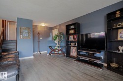 Wood-finish flooring, staircase with dark treads, light-toned ceiling, and built-in shelving units - 