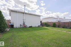 Expansive grassy yard with a stone paver pathway, mature perimeter trees, and wood fencing - 