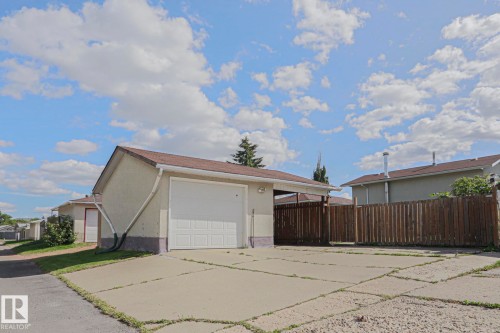 Detached garage with a paneled overhead door, concrete driveway, and partial privacy fencing - 11440 144 Avenue Nw, Edmonton, AB 