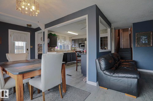 Open-concept living space featuring wood-finish flooring, dark cabinetry, and a modern light fixture - 11440 144 Avenue Nw, Edmonton, AB 