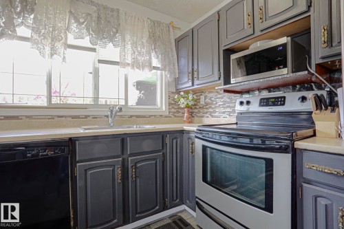 Kitchen featuring gray cabinetry, light countertops, a stainless steel range, and a built-in microwave - 11440 144 Avenue Nw, Edmonton, AB 