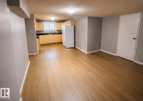 Open-concept living space with wood-finish flooring, recessed lighting, and light-toned walls - 14707 33 Street Nw, Edmonton, AB 