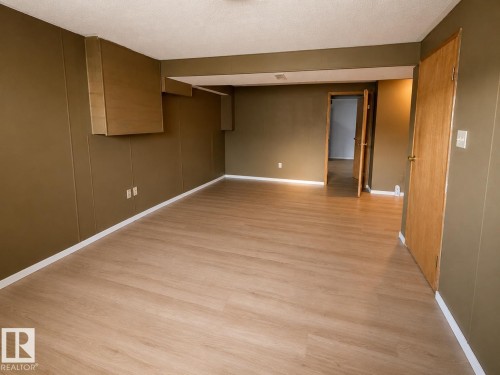 Wood-finish flooring with white trim and olive-toned walls - 14707 33 Street Nw, Edmonton, AB 