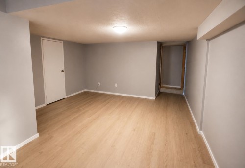 Recessed ceiling lighting illuminates a room with light wood-finish flooring and light gray walls - 14707 33 Street Nw, Edmonton, AB 