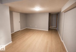 Recessed ceiling lighting illuminates a room with light wood-finish flooring and light gray walls - 