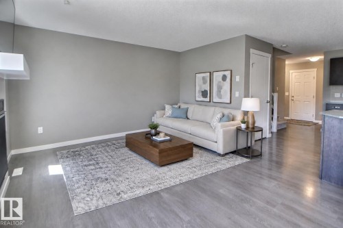 Wood-finish flooring throughout, light gray wall paint, and a built-in kitchen peninsula with a countertop - 4847 173 Avenue Nw, Edmonton, AB 