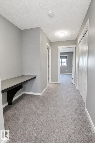 Built-in desk with dark finish support, gray walls, and light gray carpeting - 4847 173 Avenue Nw, Edmonton, AB 