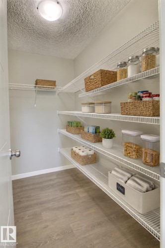 Expansive pantry featuring tiered wire shelving, wood-finish flooring, and a flush-mount ceiling light - 4847 173 Avenue Nw, Edmonton, AB 