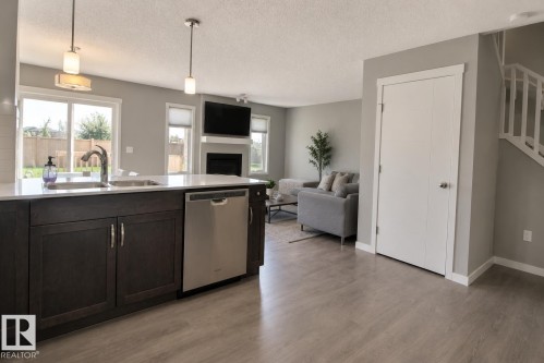 Kitchen island with a stainless steel sink, gooseneck faucet, and integrated dishwasher - 4847 173 Avenue Nw, Edmonton, AB 