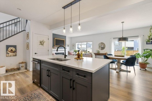 Kitchen island with a light-toned countertop, dark base cabinetry, and an integrated sink with a matte black faucet - 34 Raspberry Road, St. Albert, AB 
