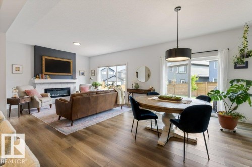 Open-concept living space with wood-finish flooring, a contemporary fireplace, and recessed lighting - 34 Raspberry Road, St. Albert, AB 