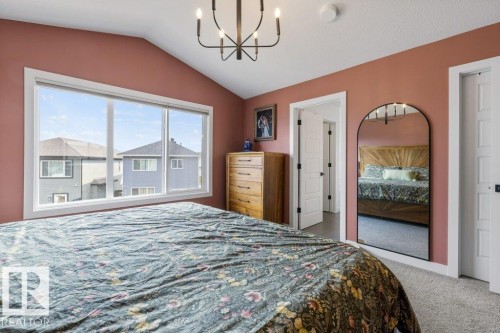 Vaulted ceiling, expansive window with white trim, wall-mounted chandelier, and paneled doors - 34 Raspberry Road, St. Albert, AB 