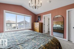 Vaulted ceiling, expansive window with white trim, wall-mounted chandelier, and paneled doors - 