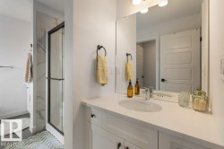 White vanity with inset cabinetry, a polished chrome faucet, a rectangular mirror, and a walk-in shower with a black-framed glass enclosure - 