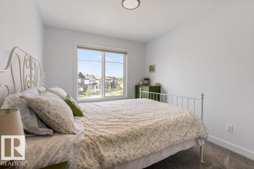 Bright interior with a large window, neutral wall paint, and textured carpeting - 34 Raspberry Road, St. Albert, AB 