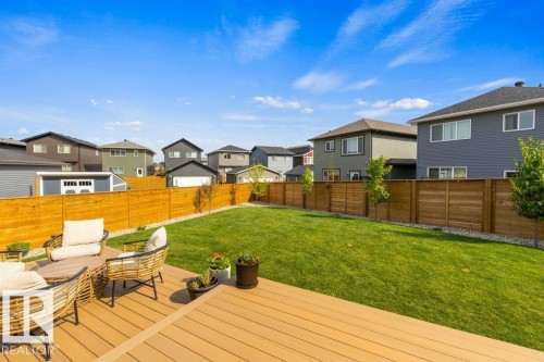 Expansive backyard featuring a manicured lawn, a full wooden privacy fence, and a composite deck - 34 Raspberry Road, St. Albert, AB 