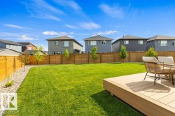 Expansive backyard featuring a lush lawn, a composite deck, and a wood fence - 