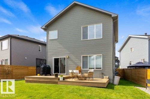 Rear exterior with grey horizontal siding, a multi-level wooden deck, and a sliding glass door - 34 Raspberry Road, St. Albert, AB 