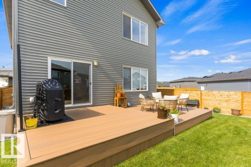 Expansive rear deck with composite decking, sliding glass door access, and a manicured lawn - 34 Raspberry Road, St. Albert, AB 