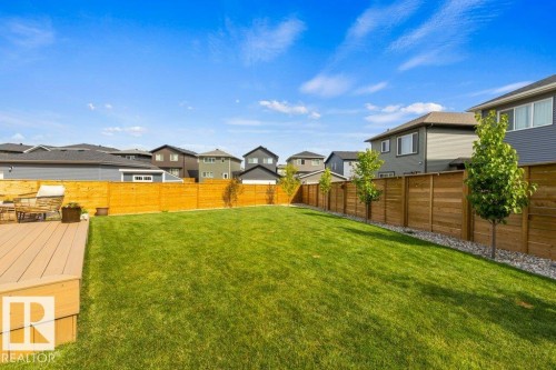 Expansive backyard featuring a manicured lawn, a wood-finish composite deck, and a perimeter wood privacy fence - 34 Raspberry Road, St. Albert, AB 